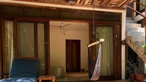 Un plafond en bois, un hamac, un mur en pierre, un banc en bois et un canapé bleu.