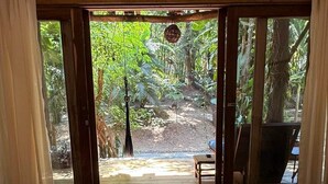 Une chambre avec un lit, un tapis rond en fibres tressées et une vue sur un jardin, visible à travers une porte-fenêtre coulissante.