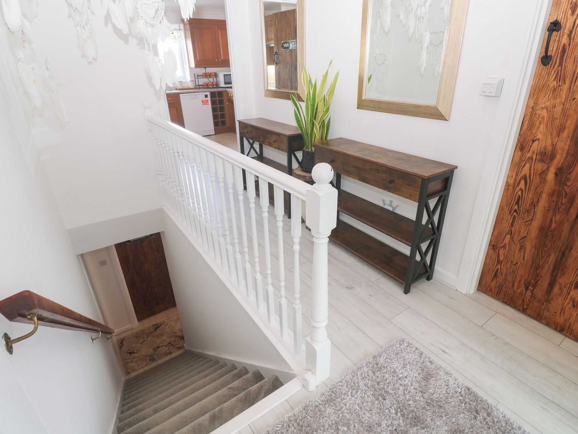 A staircase with white balusters, a wooden bench, and a potted plant in a home interior.