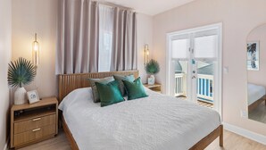A bedroom with a bed, bedside tables, curtains, a mirror, and a view through a sliding door. - 39 Topaz Cove•Remodeled•2 Pools•Free Beach Service•Fully-Stocked•Arcade Game (Miramar Beach)