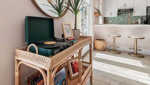A cozy living area with a record player, a wicker side table, and a mirror on the wall. - 39 Topaz Cove•Remodeled•2 Pools•Free Beach Service•Fully-Stocked•Arcade Game (Miramar Beach)