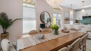 A spacious dining area with a long wooden table, wicker chairs, and a central vase. - 39 Topaz Cove•Remodeled•2 Pools•Free Beach Service•Fully-Stocked•Arcade Game (Miramar Beach)