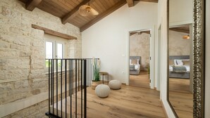 A spacious room with a stone wall, wooden beams, a balcony, and a large mirror.