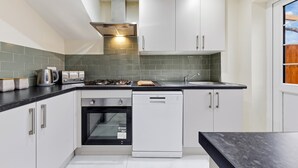 Una cocina moderna con armarios blancos, lavavajillas, horno y estufa.