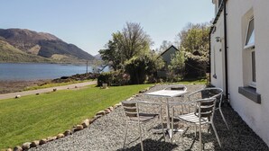 A lakeside property with a patio, outdoor seating, and a view of the lake and mountains. - Tigh a Phailean (Kyle)