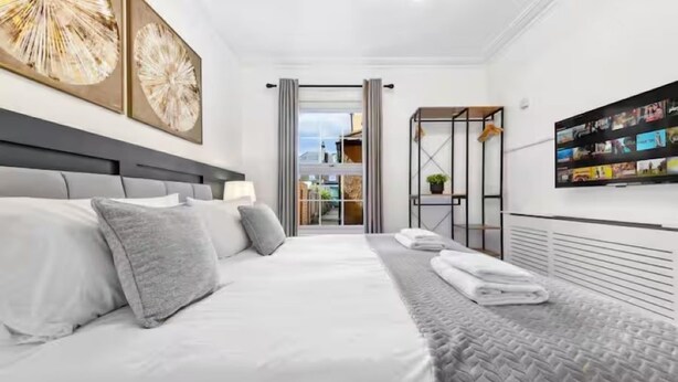 Een moderne hotelkamer met een groot bed, een aan de muur bevestigde televisie en uitzicht naar buiten.