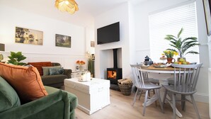 Ein gemütliches Wohnzimmer mit Kamin, ein Essbereich mit Tisch und Stühlen sowie eine Couch mit Kissen.