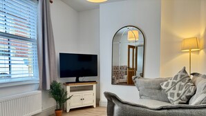 Un salon moderne avec un téléviseur à écran plat, un canapé, un miroir et une lampe.