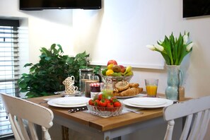 A breakfast table with plates, a bowl of strawberries, a fruit bowl, croissants, and a glass of orange juice. - The Loft - 1 BR in the Heart of Stamford, Burghley (Lincolnshire)