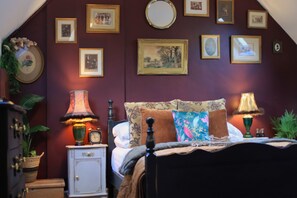A bedroom with a bed, bedside lamps, a nightstand, a dresser, and a wall decorated with framed pictures. - The Loft - 1 BR in the Heart of Stamford, Burghley (Lincolnshire)