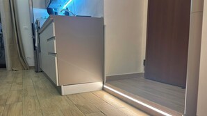 Una cocina moderna con horno empotrado y microondas, un refrigerador de acero inoxidable y piso de madera.
