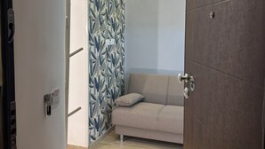 Una habitación moderna con piso de madera, un sofá beige y un papel tapiz estampado.