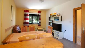 Un espacio habitable compacto con comedor, televisión y ventana con cortinas.