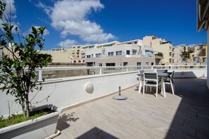 En takterrass med ett område för måltider, en krukväxt och utsikt över stadsbilden.