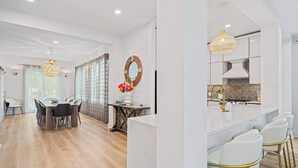 Une cuisine moderne avec des meubles blancs, un plan de travail en marbre et un luminaire suspendu.
