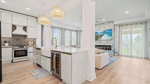 Une cuisine moderne avec des meubles blancs, un îlot central et un coin repas comprenant un canapé et une cheminée.