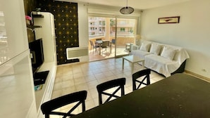A compact living space with a kitchenette, a dining area, and a sofa. - Les Calanques, one-bedroom apartment with air conditioning, large terrace and elevator (Cavalaire-sur-Mer)