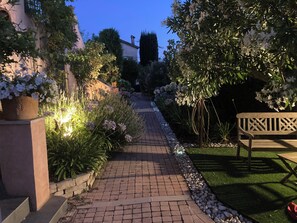 A paved garden pathway with potted plants and a bench. - A cozy little house in the vineyards, in a quiet setting, just a 1/4 walk from the beach—3 minutes by car! (Cassis)