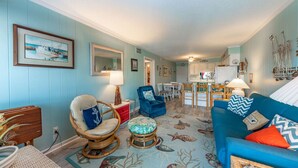 Un salón acogedor con un sofá azul, una mesa de comedor y una zona de cocina.