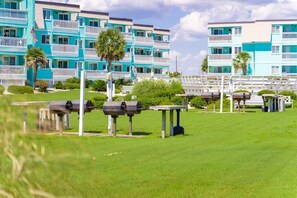 A beachfront hotel with multiple-story buildings, outdoor grills, and a well-maintained lawn. - Pelican Row: Steps to Sand • Pool • Affordable, Family Friendly, Beach Getaway (Atlantic Beach)