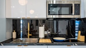 Una cucina moderna con un lavandino in acciaio inossidabile, un forno a microonde e un tagliere di legno.