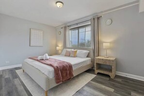 Una camera da letto moderna con un letto grande, un comodino, una finestra con tende e un lampadario a parete.