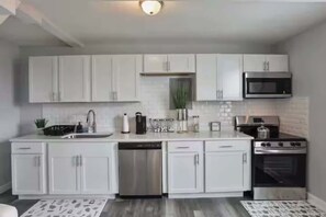 Una cucina moderna con mobili bianchi, elettrodomestici in acciaio inossidabile e un'isola centrale con lavello e piano di lavoro.