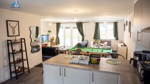 A modern living room with a pool table, a sofa, and a dining area. - The Pines Villa 1 | Spacious 3BR | Cinema, Games & EV | Parking | Sleeps 10+ (West Northamptonshire)