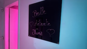 Una habitació amb un cartell a la paret que diu 'Belle démente Nina' amb un símbol de cor.