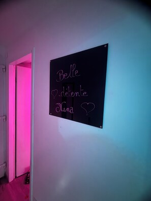 Una habitación con un letrero en la pared que dice “Belle démente Nina” con un símbolo de corazón.
