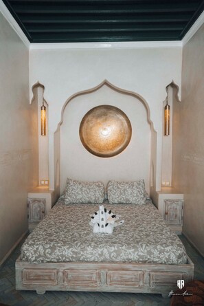 A bedroom with a bed, decorative wall, and two wall-mounted lamps. - Authentic Andalusian patio in the heart of the blue pearl of the Rif (Chefchaouen)