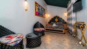 Una habitación con cama, dos sillas, una mesa y televisión.