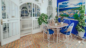 Una habitación con suelo de baldosas, muebles blancos y un cuadro de un pueblo costero.