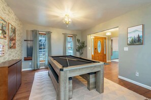A pool table in a room with a wooden cabinet, a chandelier, and a door leading to another room. - Mountain Retreat - Sauna - Hot Tub - Fire Pit (Asheville)