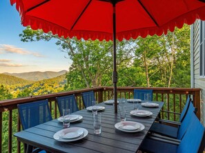 Eine Holzterrasse mit Esstisch, Stühlen und Sonnenschirm.