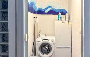 Ein kleiner Hauswirtschaftsraum mit Waschmaschine, Wäscheständer und Kühlschrank.