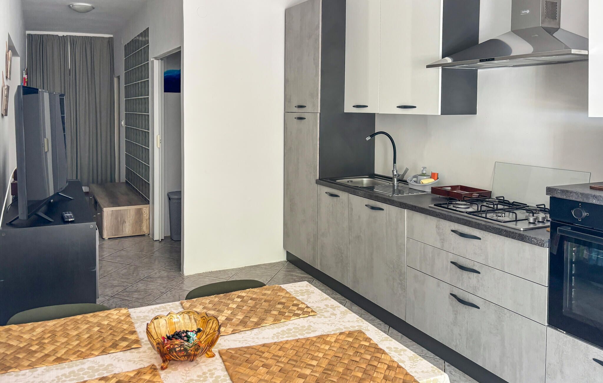 A modern kitchen with grey cabinets, a stainless steel sink, and a gas stove.
