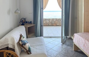 Ein Schlafzimmer mit einem Bett, einem Nachttisch, einem Globus und Blick auf das Meer durch eine Glastür.
