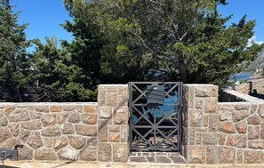 A stone wall with a metal gate, a clear sky, and trees in the background. - Nice home in Karlobag with WiFi (Karlobag)