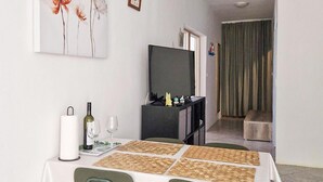 A dining area with a table set for two, a wine bottle, glasses, and a painting on the wall. - Nice home in Karlobag with WiFi (Karlobag)