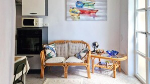 A cozy room with a wicker sofa, a small side table, and a painting of boats on the wall. - Nice home in Karlobag with WiFi (Karlobag)