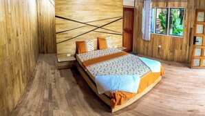 Ein Schlafzimmer aus Holz mit einem Bett, Kissen und einem Fenster mit Vorhängen.