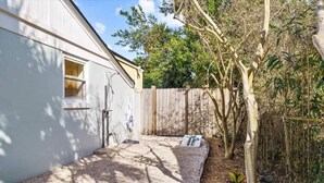 Une cour arrière avec une maison blanche, une clôture en bois et un arbre.