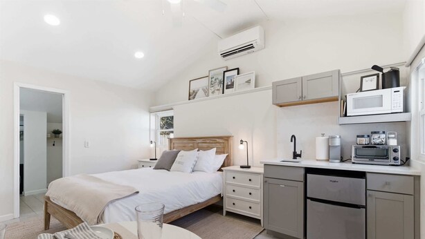 Une chambre moderne avec un lit, des tables de chevet et une petite kitchenette.