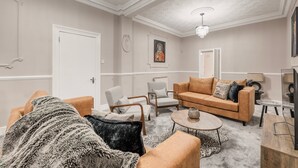 Una sala de estar con sofá, sillas, una mesa de centro y televisor.