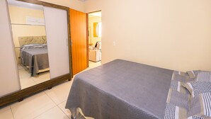 A bedroom with a bed, a mirror, and a wardrobe. - Casa com Piscina e Churrasqueira em Arembepe (Camaçari)