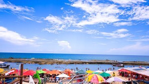 A beach with colorful umbrellas and boats. - Casa com Piscina e Churrasqueira em Arembepe (Camaçari)