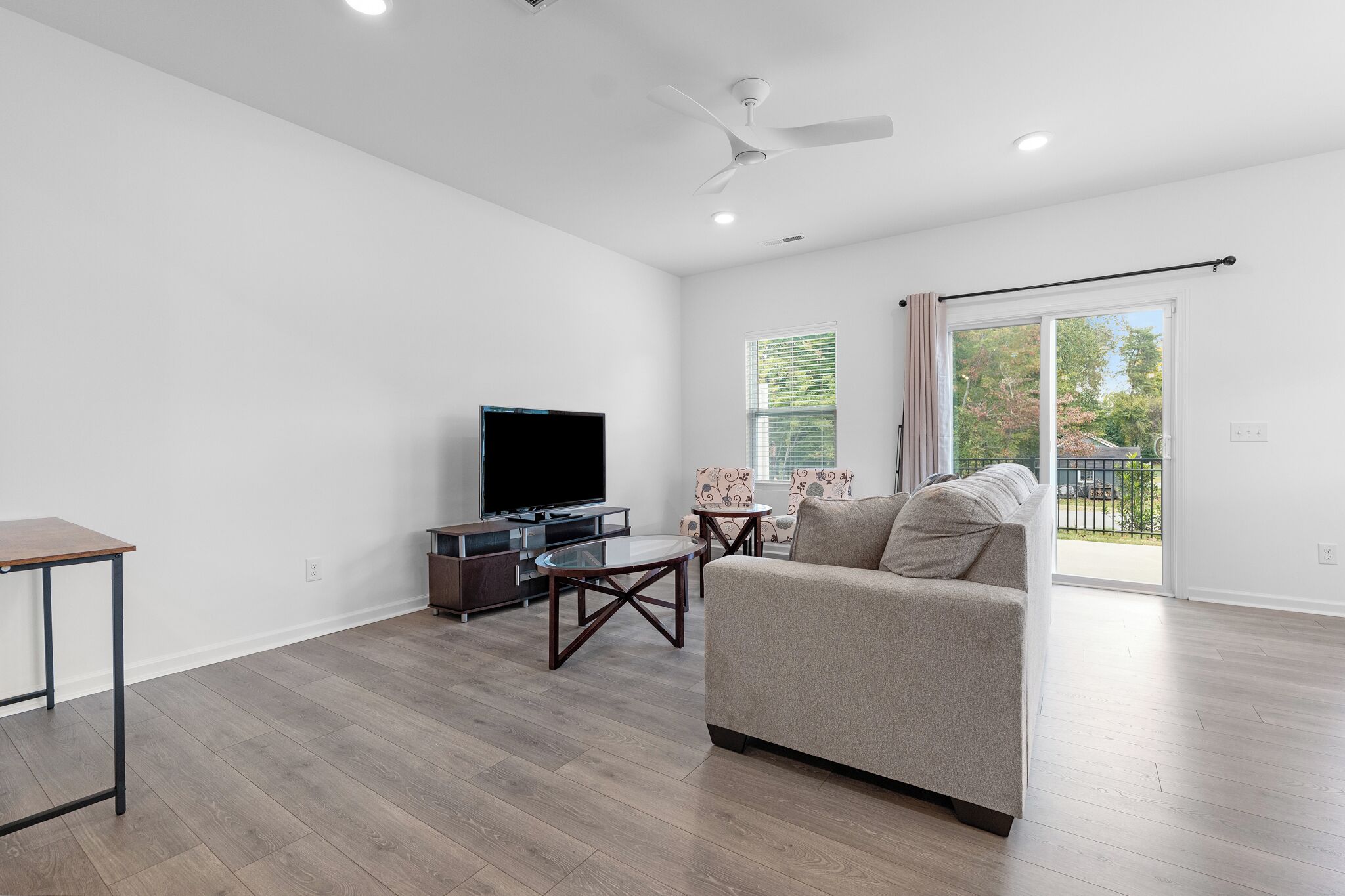 Un salon moderne avec un téléviseur à écran plat, un canapé, une table basse et un ventilateur de plafond.