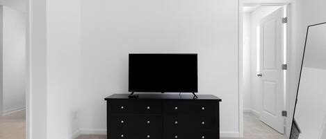 A room with a black TV stand, a door, and a white wall.