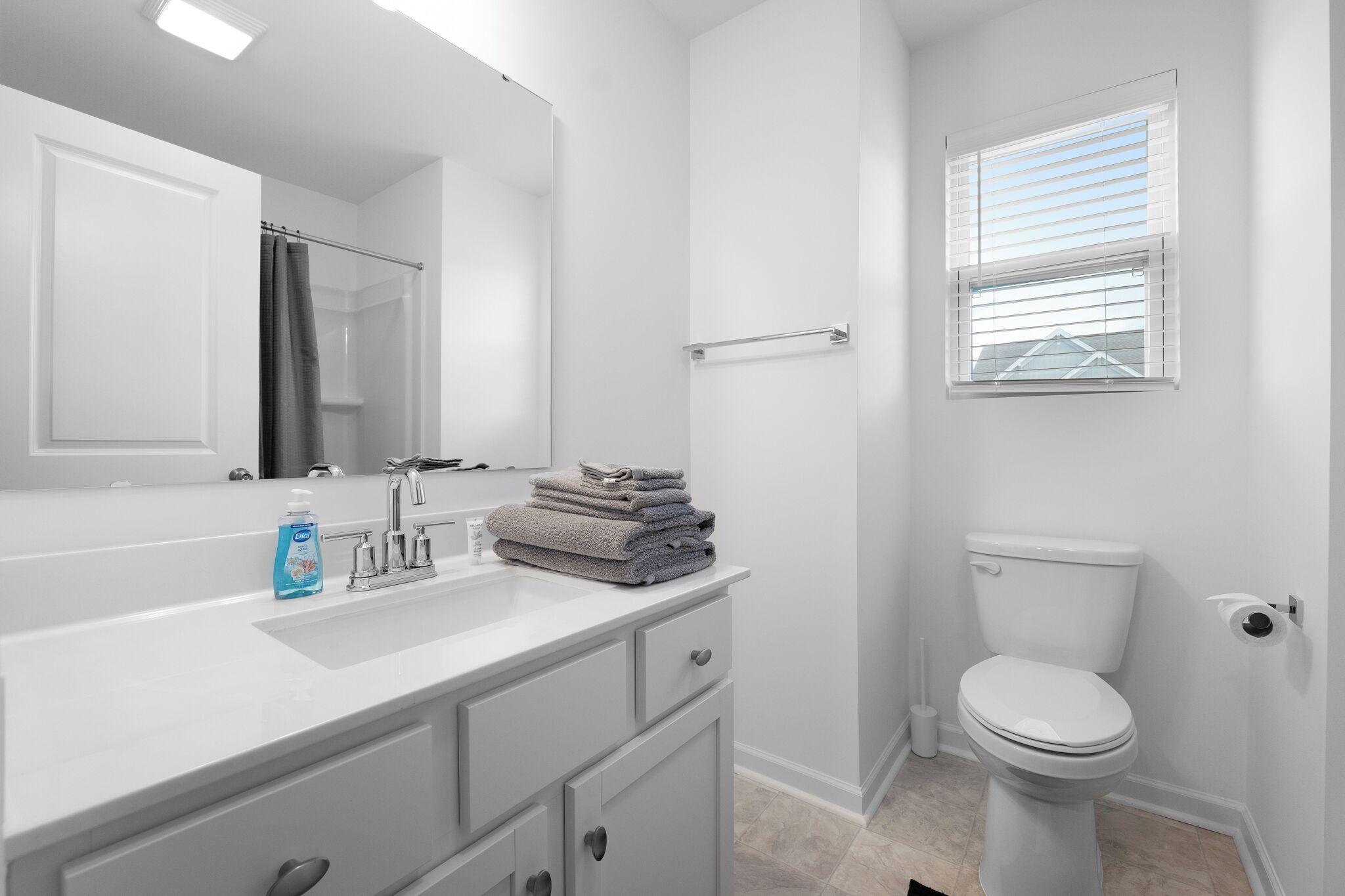 A modern bathroom with a white sink, mirror, and toilet.